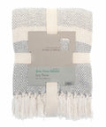 A folded grey and white woven throw blanket with fringes, tagged with product information from Home & Living, named "HL208.