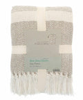 A folded throw blanket featuring a beige and white herringbone pattern with fringe, packaged with a label from Home & Living, model HL208.