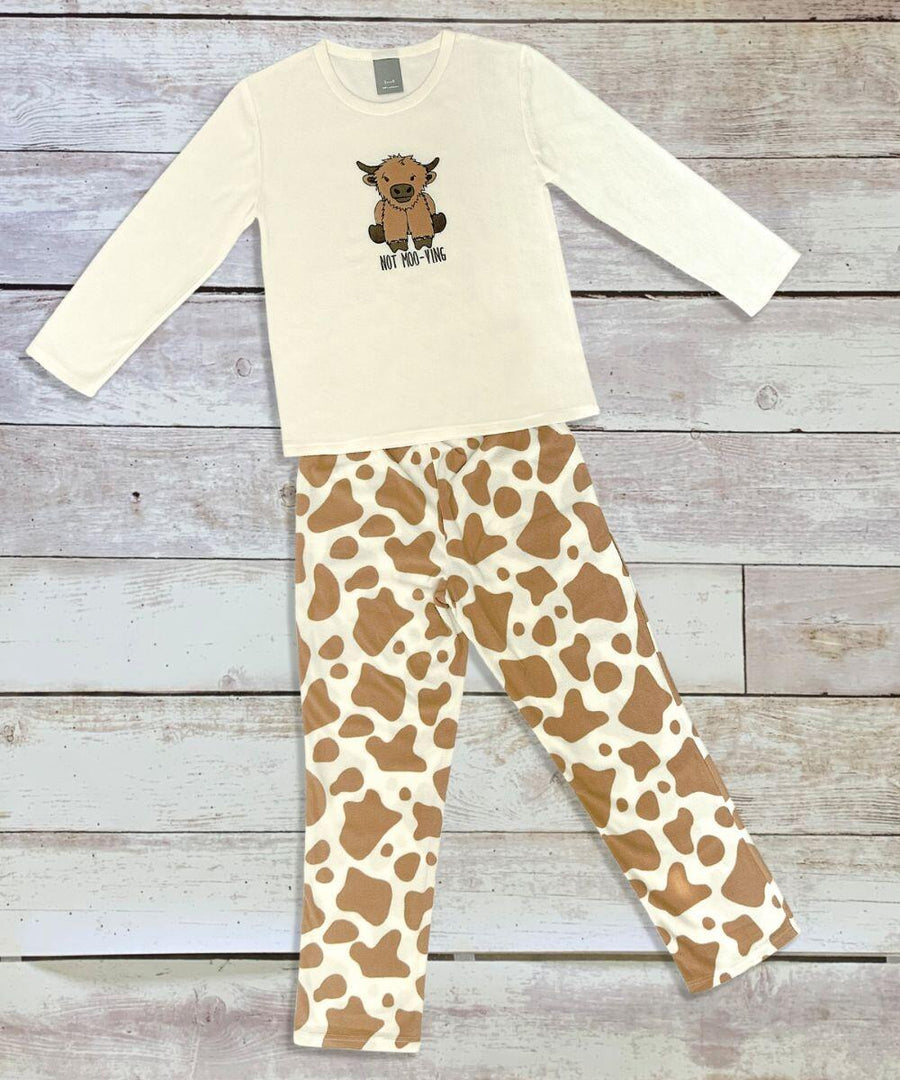 Product HL219, a white long-sleeve pajama top featuring a cow print design with a brown cow graphic, is paired with matching white and brown cow print pants from the Home & Living brand, displayed on a wooden background.
