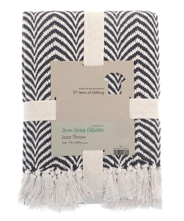 A folded black and white chevron-patterned recycled mixed-fabric throw with white fringe, wrapped in a beige band labelled “Home & Living, Recycled mixed-fabric throw, Size: 170 x 200 cm.”.