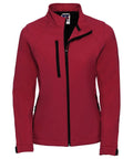 The Russell J140F women's jacket features a high collar, black zipper, and two zippered pockets on both the chest and sides. It is crafted in a soft and fitted material, making it ideal for casual or outdoor wear. The jacket comes in a vibrant red color.