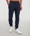 A person wearing navy blue jogger pants and white sneakers is standing on a plain background. Their upper body, dressed in a Russell J268M, is not fully visible.