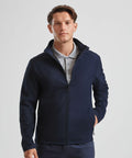 A man wearing a navy blue Russell J420M zip-up jacket over a grey polo shirt is standing and looking at the camera.