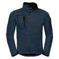 The J520M by Russell is a dark blue jacket with a sporty, fitted design. It features long sleeves, a front zipper, and a stand-up collar. The jacket includes zippered pockets on the chest and sides, along with an extra pocket on the left sleeve.