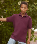 A young boy wearing a Russell J539B stands outdoors near some green foliage.