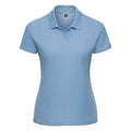 A J539F polo shirt by Russell in light blue, featuring short sleeves, a collar, and a button placket against a white background. It is adorned with a small logo embroidered on the left side of the chest.