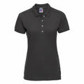 The Russell J566F, a plain black short-sleeve polo shirt featuring a button-up collar, is displayed against a white background.