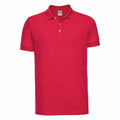 A plain red polo shirt from Russell, model J566M, featuring a collar and three buttons. This short-sleeved shirt is showcased against a white background.