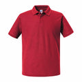 A J570M polo shirt by Russell in plain red, featuring short sleeves and a collar, displayed from the front against a white background.