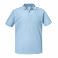 The J570M by Russell is a light blue polo shirt featuring short sleeves, a collar, and a buttoned placket at the neck. Displayed against a white background, the shirt appears to be crafted from soft, woven fabric.