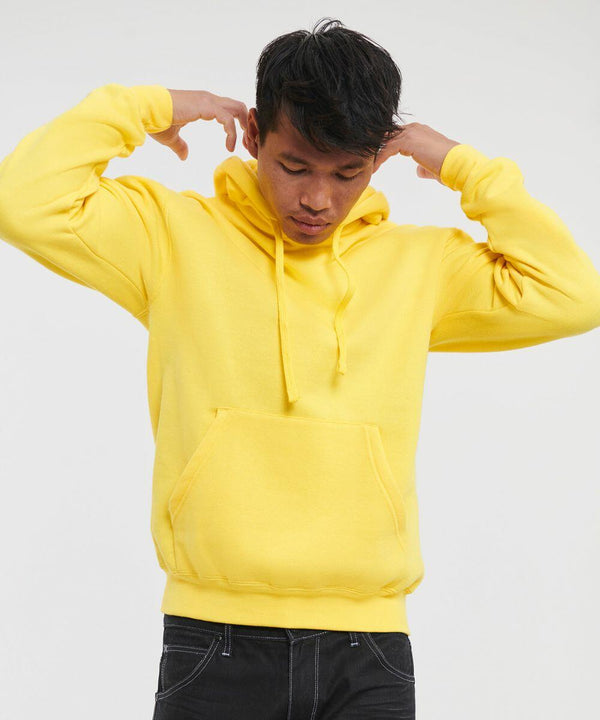Person wearing a yellow Russell J575M hoodie with the hood down, standing against a plain background, adjusting the drawstrings while looking down.