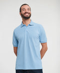 A man wearing a light blue J599M by Russell, smiling and looking upwards, his hands behind his back.