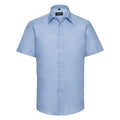 A light blue short-sleeve dress shirt from the Russell Collection, product name J923M, featuring buttons down the front and a pointed collar. The shirt is shown against a plain white background.