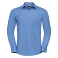 The Russell Collection J924M is a long-sleeved blue dress shirt featuring a collar and button-down front, displayed against a white background.