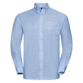 A light blue button-up shirt, J932M by Russell Collection, featuring a collar and long sleeves. It includes a chest pocket on the left side and has a smooth fabric with white buttons.