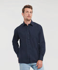 A man wearing a navy blue Russell J934M and light blue jeans stands against a plain, light background.