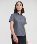 A person wearing a short-sleeved, button-up gray shirt, Russell's J935F, stands against a plain, light background.