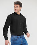 A man wearing a black J936M button-up shirt by Russell and blue jeans stands against a plain background.