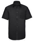 J957M by Russell Collection: A black short-sleeve button-up shirt featuring a front chest pocket, set against a white background.
