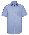 The Russell Collection's J957M shirt is a light blue, short-sleeved button-up with a front chest pocket, showcased against a plain white background.
