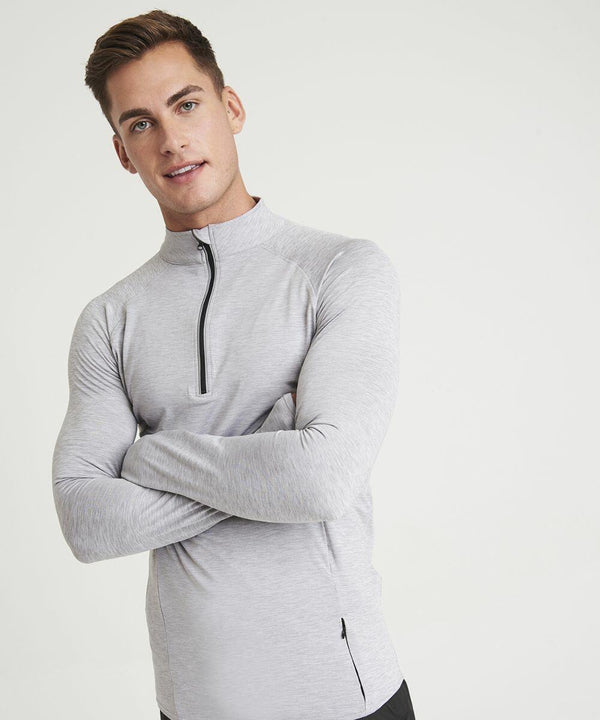 A man in a light gray AWDis Just Cool JC030 long-sleeve athletic top with a half-zipper stands with arms crossed against a plain white background.