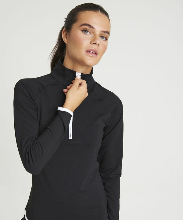 A person wearing a black JC036 long-sleeved zip-up top by AWDis Just Cool is adjusting the zipper, looking slightly upward, against a plain white background.