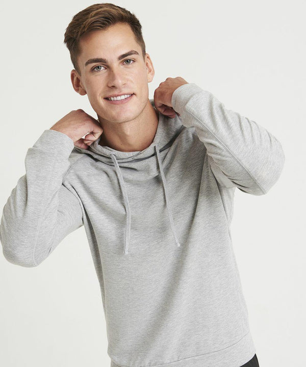 A person wearing a light gray JC052 hoodie by AWDis Just Cool looks at the camera while holding the hood strings with both hands.