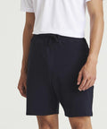 A person wearing a white short-sleeve AWDis Just Cool JC072 shirt and navy blue drawstring AWDis Just Cool JC072 shorts.