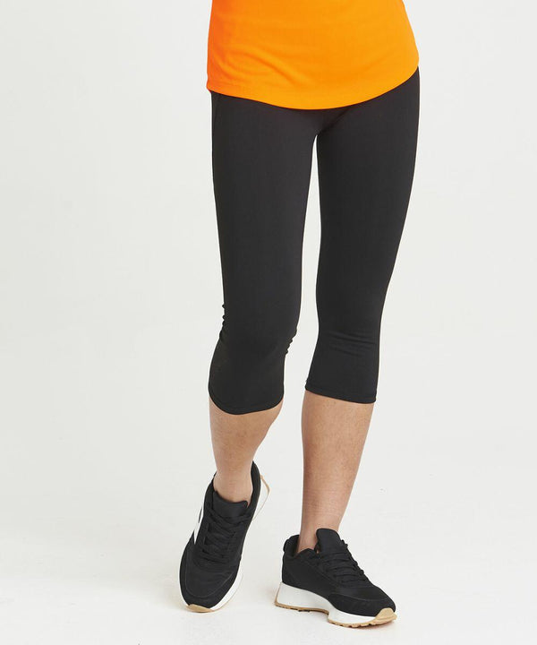 A person wearing black leggings, black sneakers, and an orange **JC086 by AWDis Just Cool** stands against a white background.