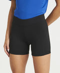 A person wearing black AWDis Just Cool JC088 shorts and a blue top is shown from the waist down, with their left hand resting in their pocket.