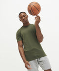 A person in an AWDis Just Cool JC110 green t-shirt and gray shorts is spinning a basketball on their finger.