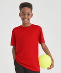 A smiling boy wearing a red t-shirt holds a large, yellow AWDis Just Cool JC20J in his right hand.