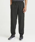 A person is wearing black JC281 jogger pants by AWDis Just Cool and gray athletic shoes, standing against a plain white background.