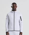 A man faces forward in a light grey AWDis Just Cool Adapt fleece zoodie with a black zip and matching trousers, set against a plain light background.