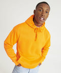 A person wearing an AWDis Just Hoods JH004 and light-wash jeans stands against a plain background, looking directly at the camera.
