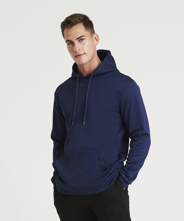 A man wearing an AWDis Just Hoods JH006 with his hands in the front pocket, standing against a plain white background.