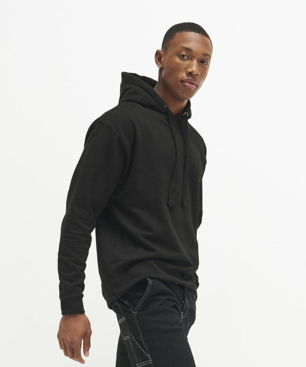 A person wearing a black AWDis Just Hoods JH011 hoodie and black pants stands against a plain white background.