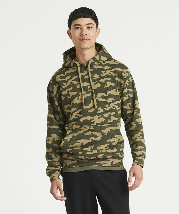 Person wearing an AWDis Just Hoods JH014 camouflage hoodie with drawstrings and black pants, standing against a plain white background.