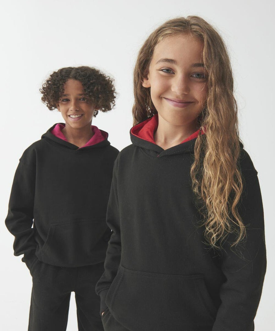 Two children wearing black AWDis Just Hoods JH03J hoodies with red linings stand smiling in front of a plain white background.