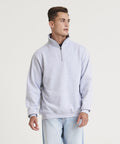 A person wearing a light gray AWDis Just Hoods JH046 quarter-zip pullover and light blue jeans stands against a plain white background.