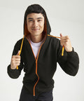 A person wearing an AWDis Just Hoods JH053 with an orange zipper and orange drawstrings holds the hood and smiles at the camera.