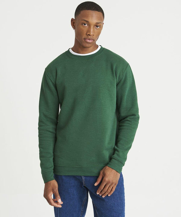 Person in an AWDis Just Hoods JH230 green sweatshirt and blue jeans stands against a plain white background, looking at the camera with a neutral expression.
