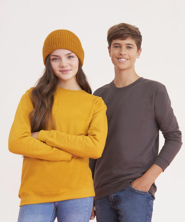 Two young people standing side by side against a plain background. The person on the left wears a yellow beanie and matching JH30J sweatshirt from AWDis Just Hoods; the person on the right wears a gray sweatshirt.