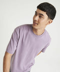 A person with short dark hair wearing an AWDis Just T's JT009 looks over their left shoulder against a plain white background.