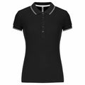 The KB251 by Kariban is a black short-sleeved polo shirt featuring a collar, button-up front, and white trim on the collar and sleeves.
