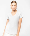 A woman wearing a light gray Kariban KB381 V-neck T-shirt and hoop earrings stands against a plain white background.