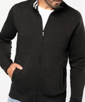 Man wearing a black Kariban KB456 zip-up jacket with a white t-shirt underneath, one hand in the jacket pocket.