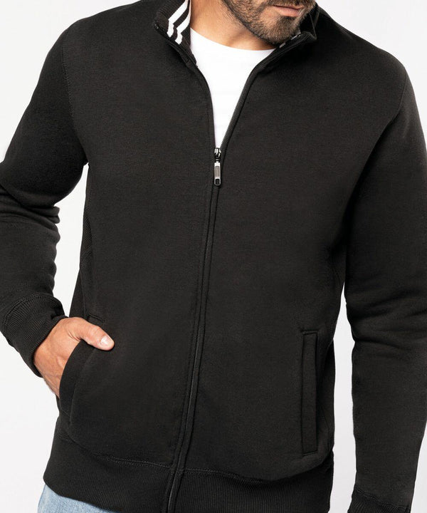 Man wearing a black Kariban KB456 zip-up jacket with a white t-shirt underneath, one hand in the jacket pocket.