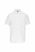 Introducing the KB535 by Kariban, a stylish short-sleeve white button-up shirt, featuring a crisp collar and a single chest pocket, displayed against a minimalist backdrop.