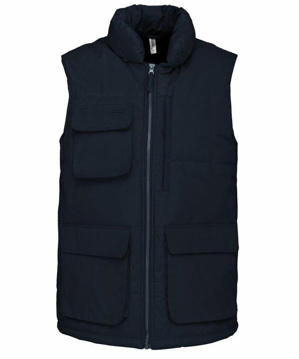 A navy blue sleeveless puffer vest with multiple front pockets and a zip-up closure, the Kariban KB615.